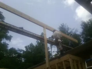 Carpenter setting a ridge beam over a new addition frame — Ice Dam Removal by Roofing Brothers in Day
