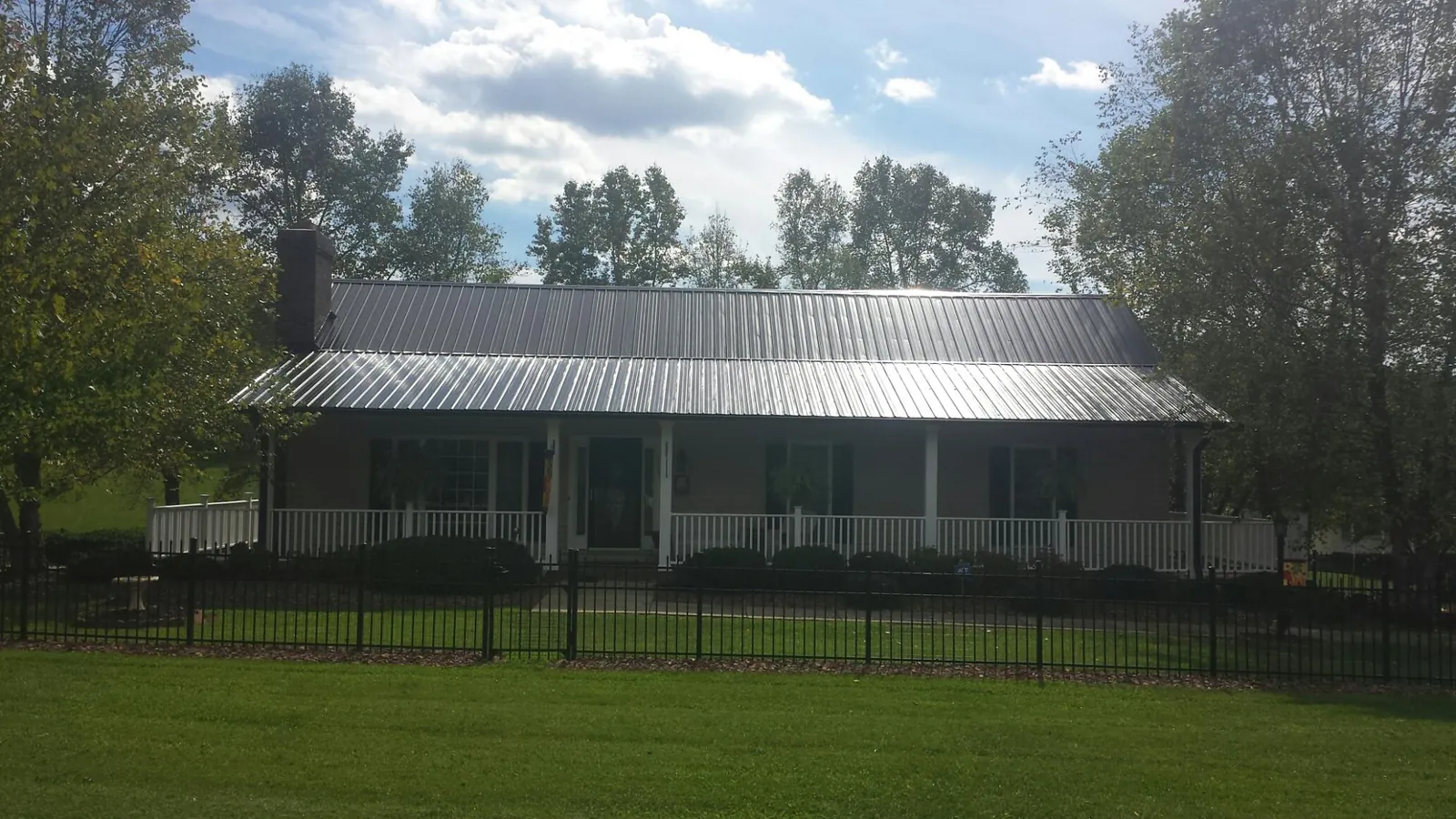 Gray metal roof on a brick ranch with a full width front porch — Gutter Guard Installation work by our crew in Day