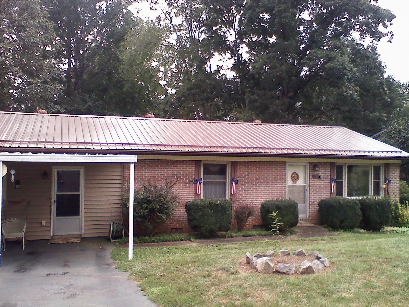 Bronze metal roof and carport on a brick ranch home — Roof Repair work by our crew in Day