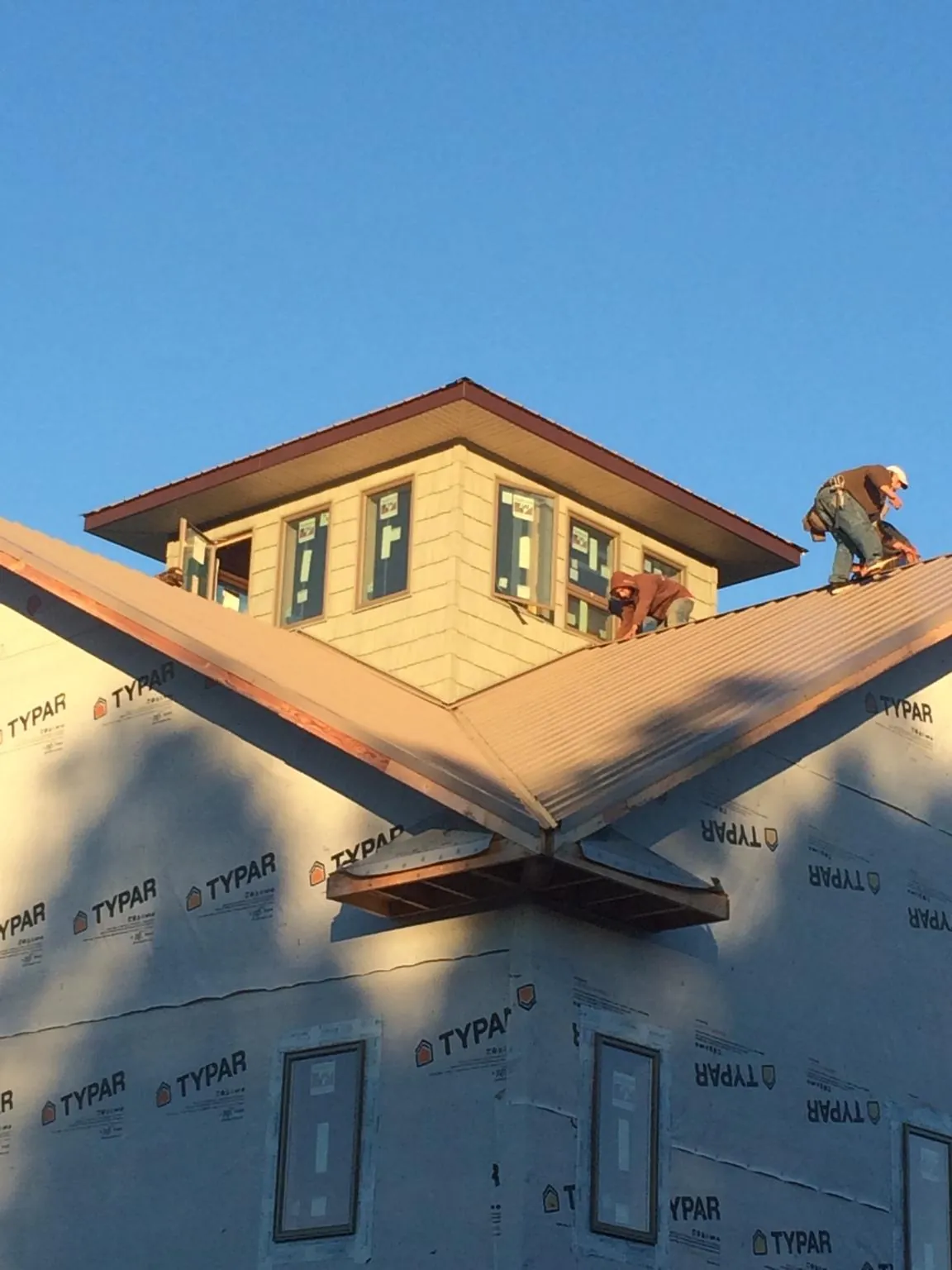 Roofers working around a rooftop cupola on a new metal roof at sunset — Roof Waterproofing in Day by Roofing Brothers
